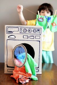 Little kid playing with fake laundry machine.