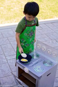 Little boy cooking on fake kitchen toy set.