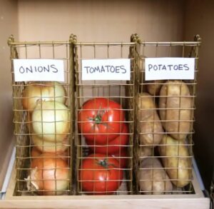 Onions, tomatoes, and potatoes in kitchen baskets.