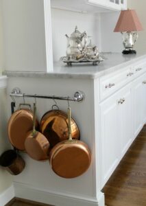 Pots and pans hanging off side of kitchen counter.
