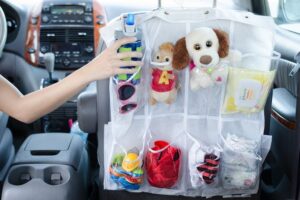 Woman putting toy in toy organizer in back seat of car.