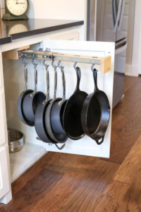 Pans hanging inside of kitchen cabinet.