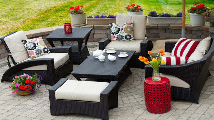 A woven patio set with white cushions.