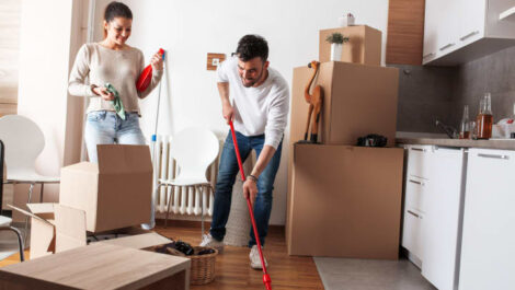 A couple packing and cleaning their apartment kitchen.