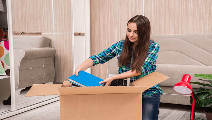 A woman putting notebooks in a moving box.