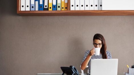 A woman sipping coffee at a desk.