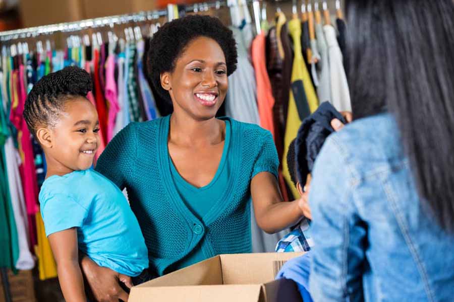 A woman holds her daughter as she donates used items.