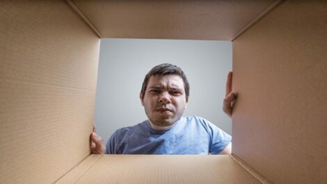 A confused man looking in a moving box.