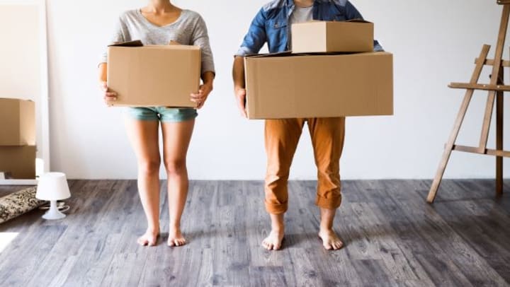 A couple holding moving boxes.