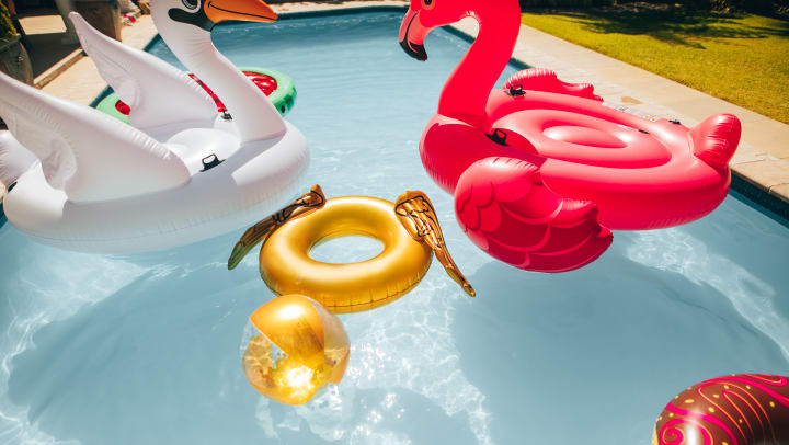 A flamingo, swan, and other floaties in a pool.