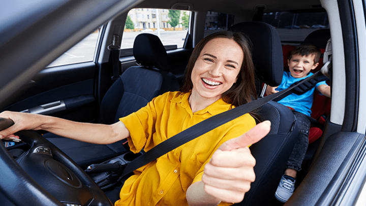 A mom and her son giving a thumbs up in a car.