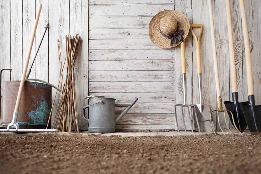 Farm tools stood up outside shed.