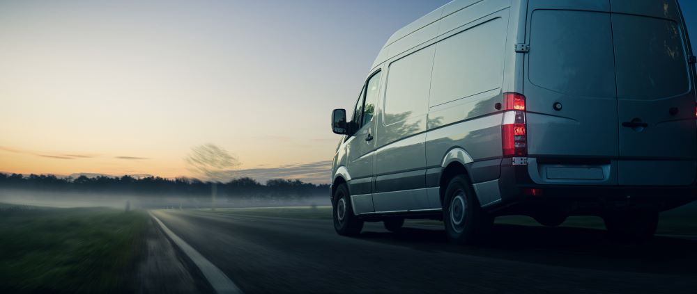 White van driving on a highway in the early morning.