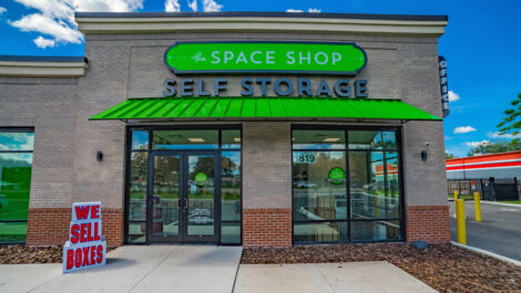 Outside of Space Shop Location With Large windows and Doors and a We Sell Boxes Sign.