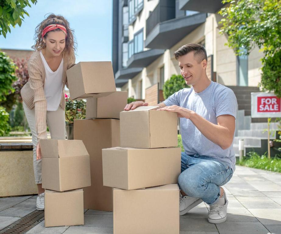 Couple stacking moving boxes outside of previous house.