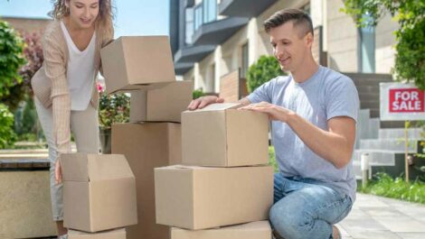 Couple stacking moving boxes outside of previous house.