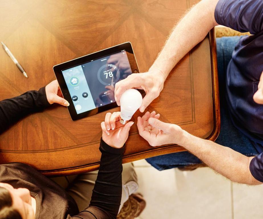 Man showing another man about smart light bulb.