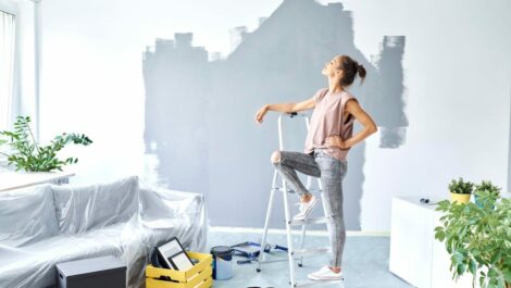 Woman standing against a ladder taking a break from painting her house.