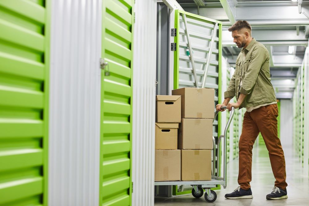 Man moving storage boxes into storage unit.