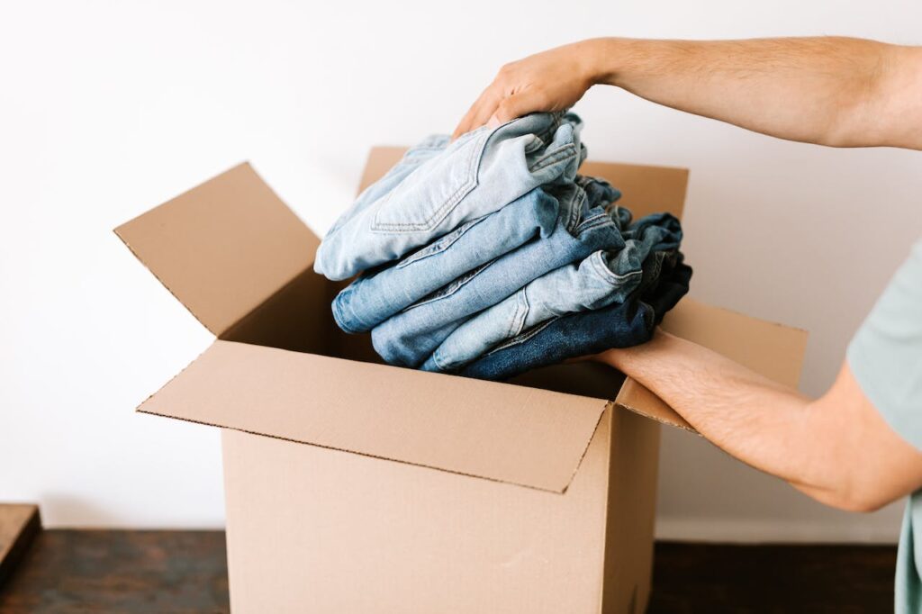A person putting jeans in a storage box.