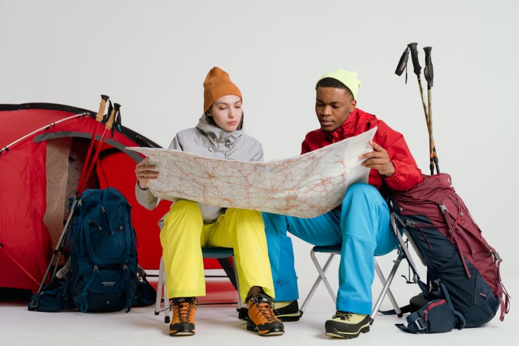 A man and a woman looking at a map next to camping equipment